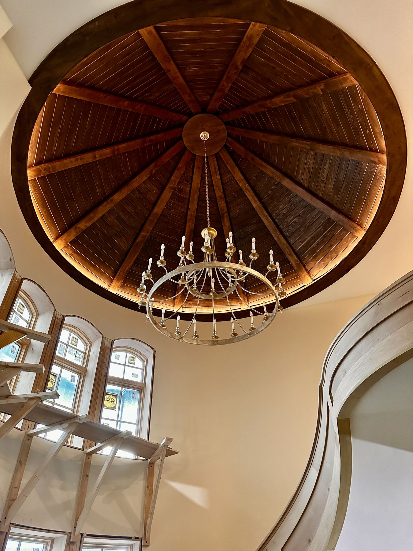 Radial wood dome ceiling with a chandelier above a curved stair